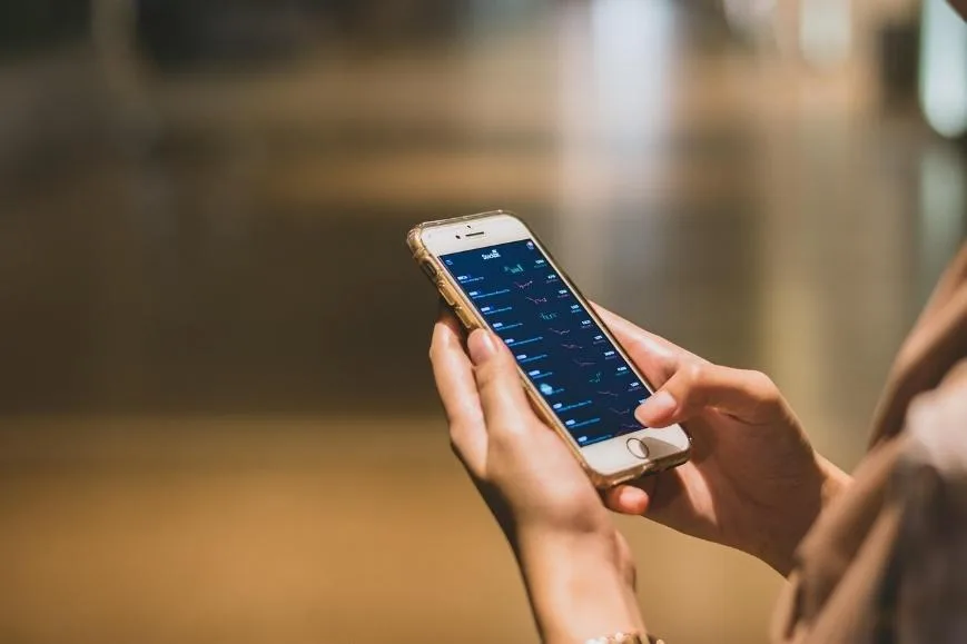 Hands holding a smartphone over a desk while checking a message